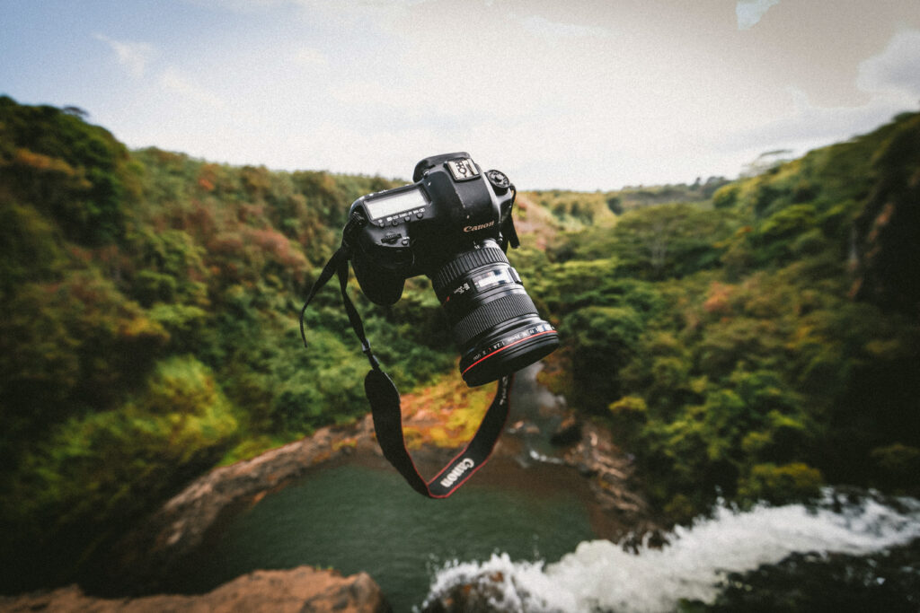 Jakob Owens' camera thrown into the air with a forest and river in the back ground.